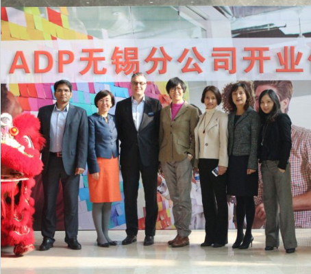 group of ADP China associates standing between red and yellow Chinese lions