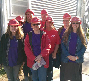 group of ADP volunteers wearing red construction hardhats