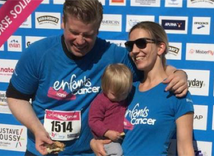 a young couple holding a small child; participanting in 'enfants sans cancer' event