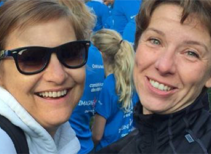 two women standing in front of other people in blue T-shirts