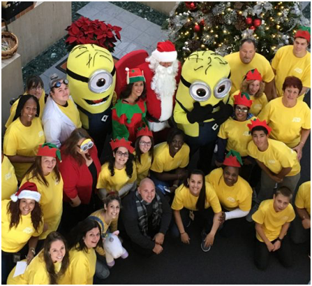 group of ADP associates in yellow T-shirts gathered around Santa Claus, an elf, and two minion characters from the movie Despicable Me
