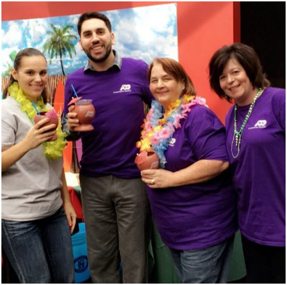 group of ADP associates in purple T-shirts holding tropical drinks