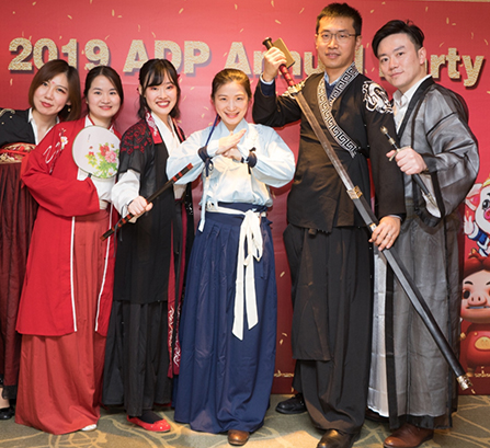 Men and women dressed in traditional Chinese fashion posing for a photo in front of a sign that reads 2019 ADP Annual Party