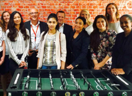 group of ADP associates standing behind a foosball table