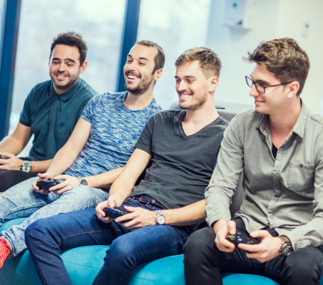 four young guys with game consoles in their hands