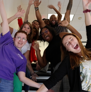 group of people in stairwell, with their hands in the air and celebratory smiles