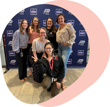 six women smiling for group photo in front of ADP banner