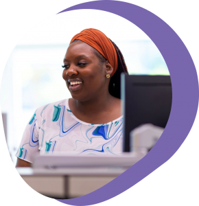 woman wearing orange headband, at work station smiling