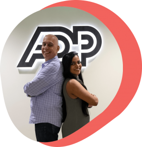 man and woman standing back to back in front of ADP logo, smiling at camera