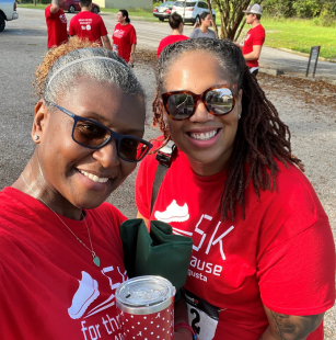 two women wearing sunglasses taking a selfie at an outdoor work event
