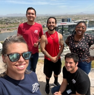 two women and three men outdoors in workout clothes taking a selfie